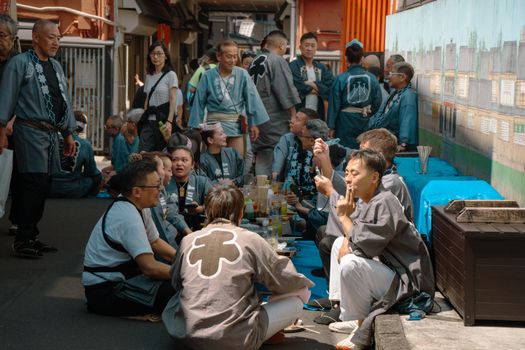A lively scene of people in traditional attire gathering in a Tokyo alleyway.