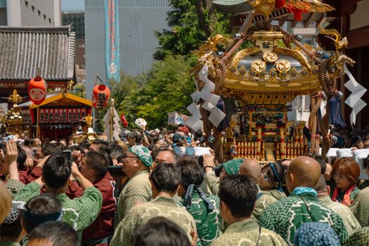 Vibrant festival procession with ornately decorated mikoshi in Tokyo, Japan.