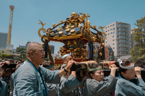 Free Participants carry a mikoshi during a lively Tokyo festival on a sunny day. Stock Photo