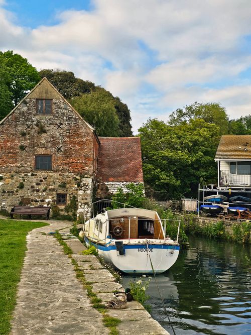 Free Charming canal scene with historic stone buildings and classic boats, ideal for travel and lifestyle themes. Stock Photo