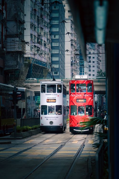 Free A white and red double-decker tram navigating the streets of Hong Kong Island, surrounded by urban structures. Stock Photo