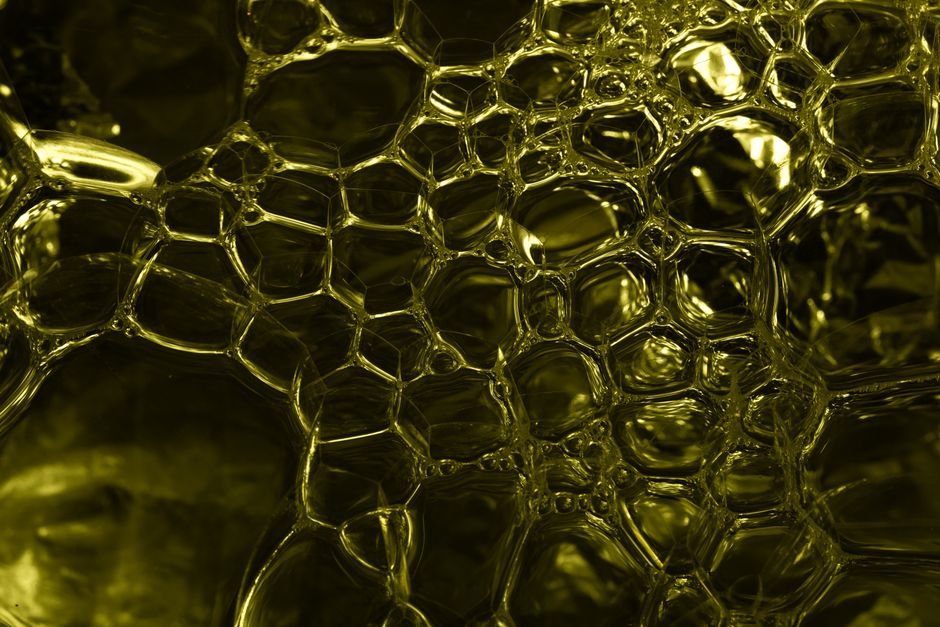 Macro shot of abstract yellow bubbles in liquid forming a honeycomb pattern, ideal for creative backgrounds.