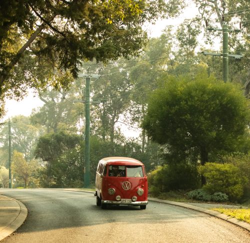 Free Explore the tranquility of a forest road with a classic red van, highlighting nostalgic travel. Stock Photo