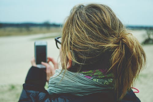 無料 白いandroidスマートフォンを使用している女性 写真素材