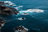 从空中俯瞰墨尔本岩石海岸线，蔚蓝的海水与嶙峋的岩层构成一幅壮观的景象