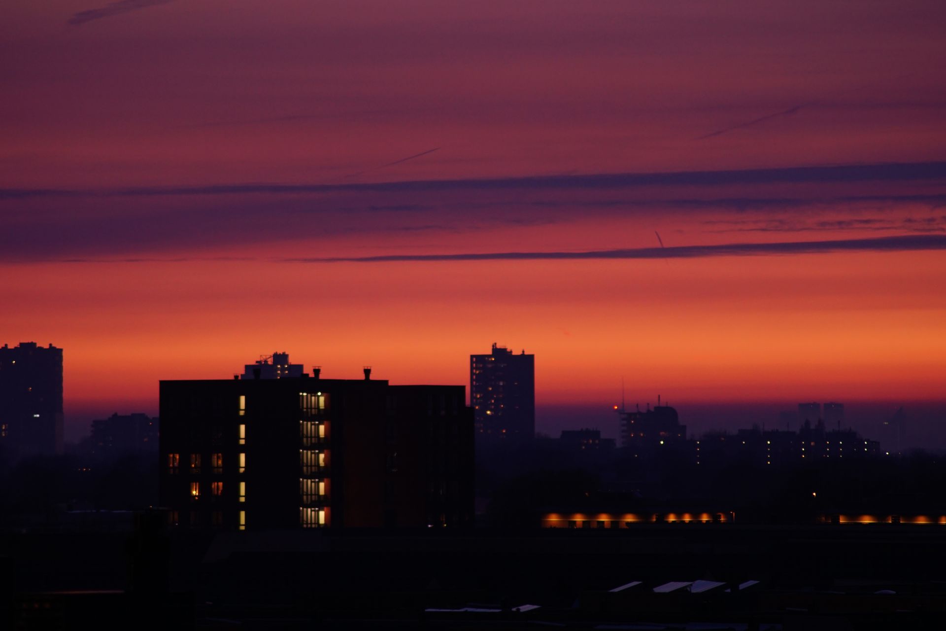 A stunning urban skyline silhouette against a vibrant sunset sky, capturing the dramatic transition from day to night.