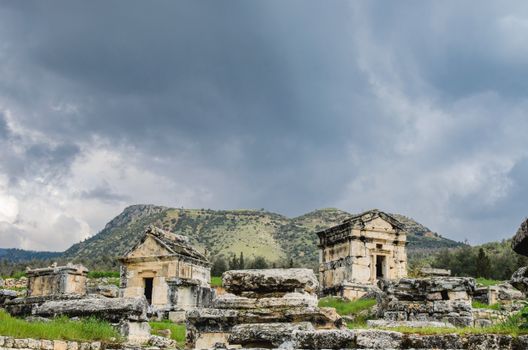 Explore the ancient ruins of Hierapolis in Pamukkale, Türkiye, beneath dramatic skies and scenic landscapes.