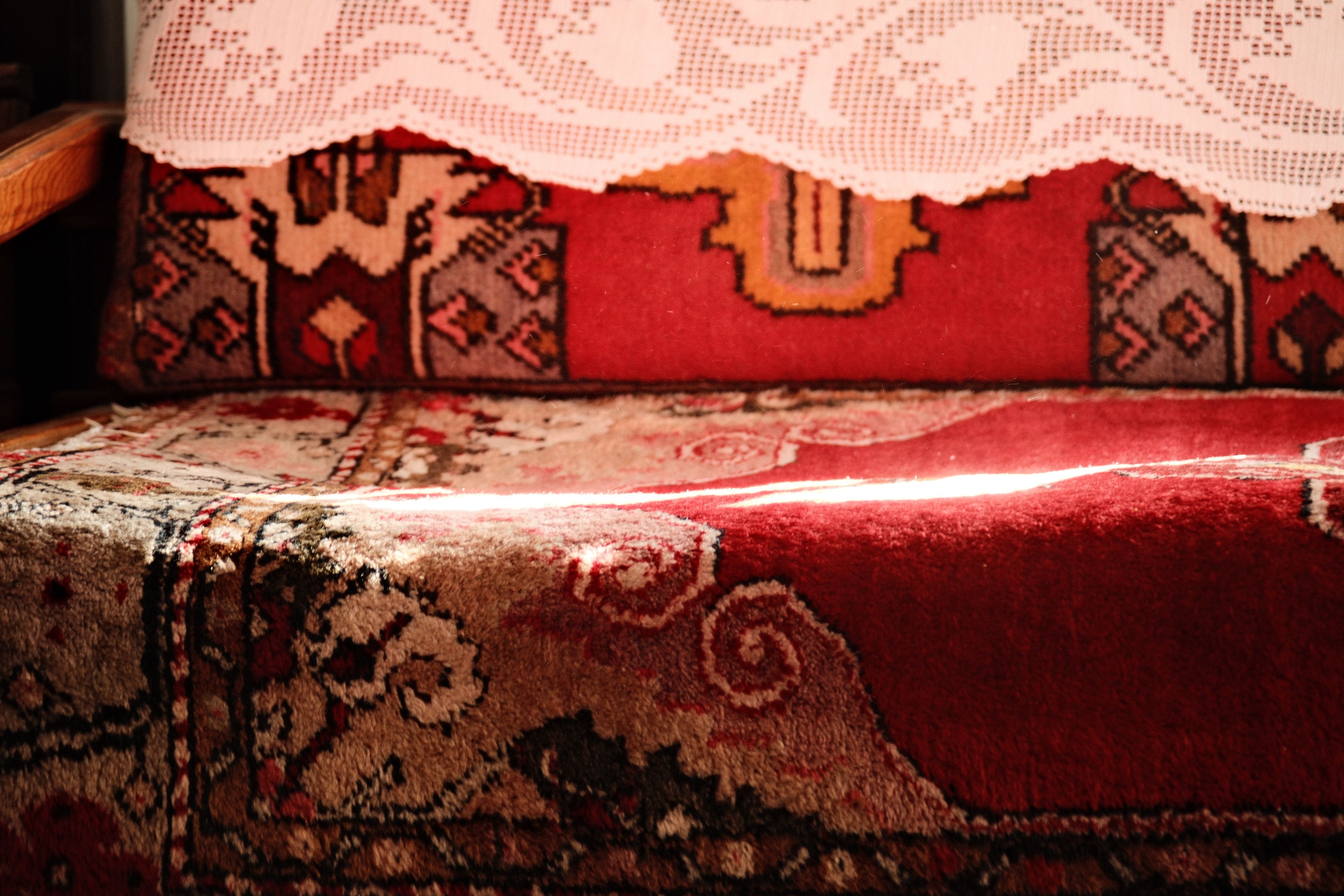 Warm natural light on a traditional upholstered chair with intricate red patterns. Cozy and artistic.