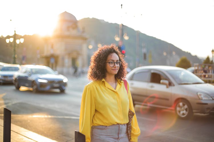 Woman In Yellow Button Up Shirt And Blue Jeans Walking Down Side Street