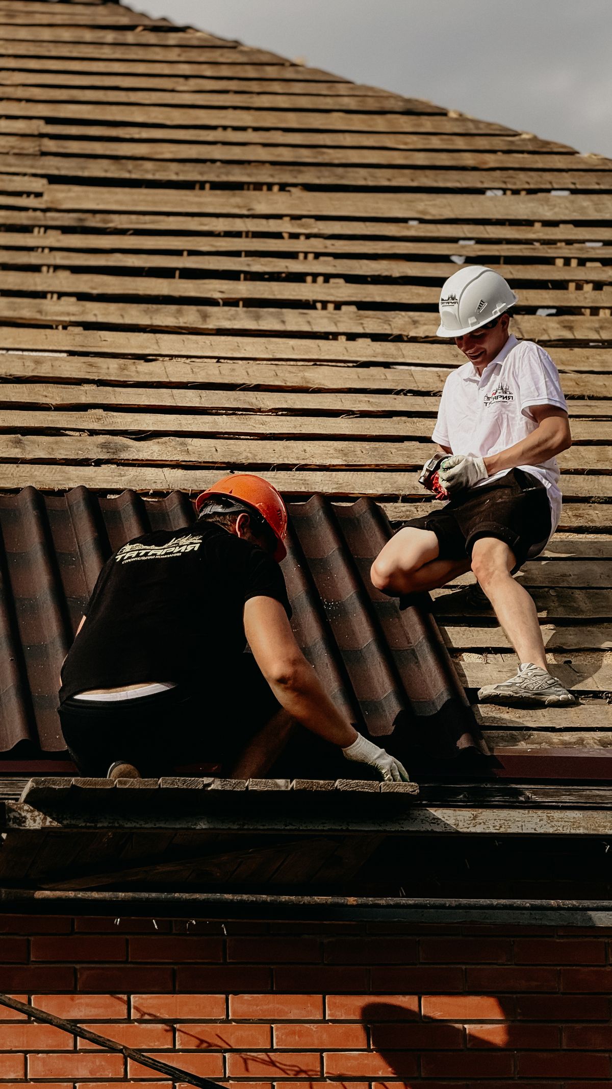 Dos profesionales reparando tejas en un tejado