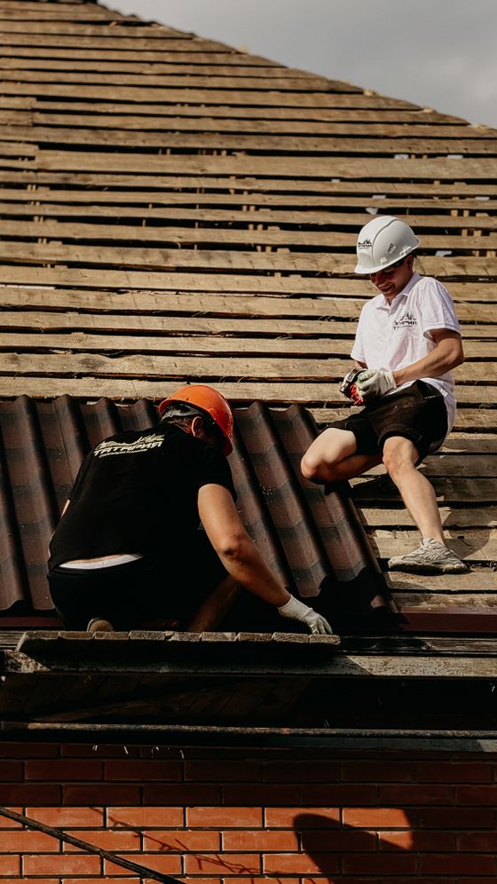 Crew replacing roof tiles on a brick house