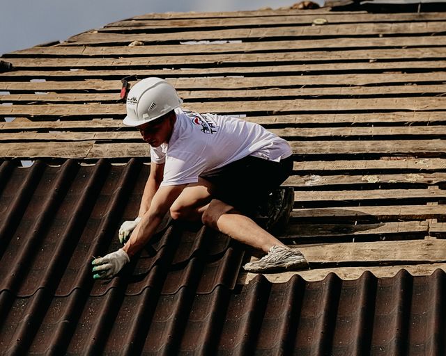 Installing roof tiles Construction worker installing roof tiles on a sloped rooftop
