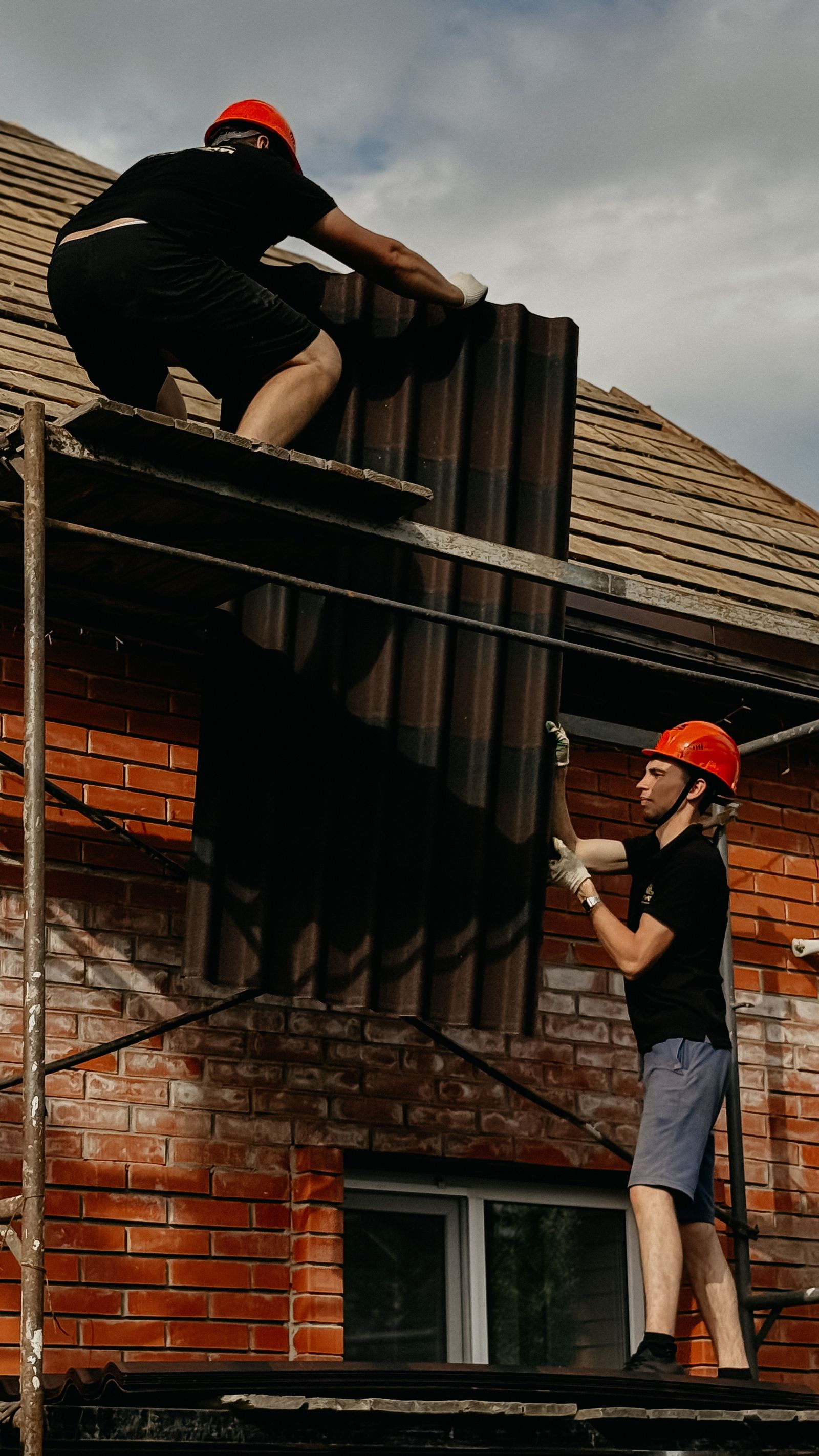 Builders installing the roof of a new upper floor from scaffolding
