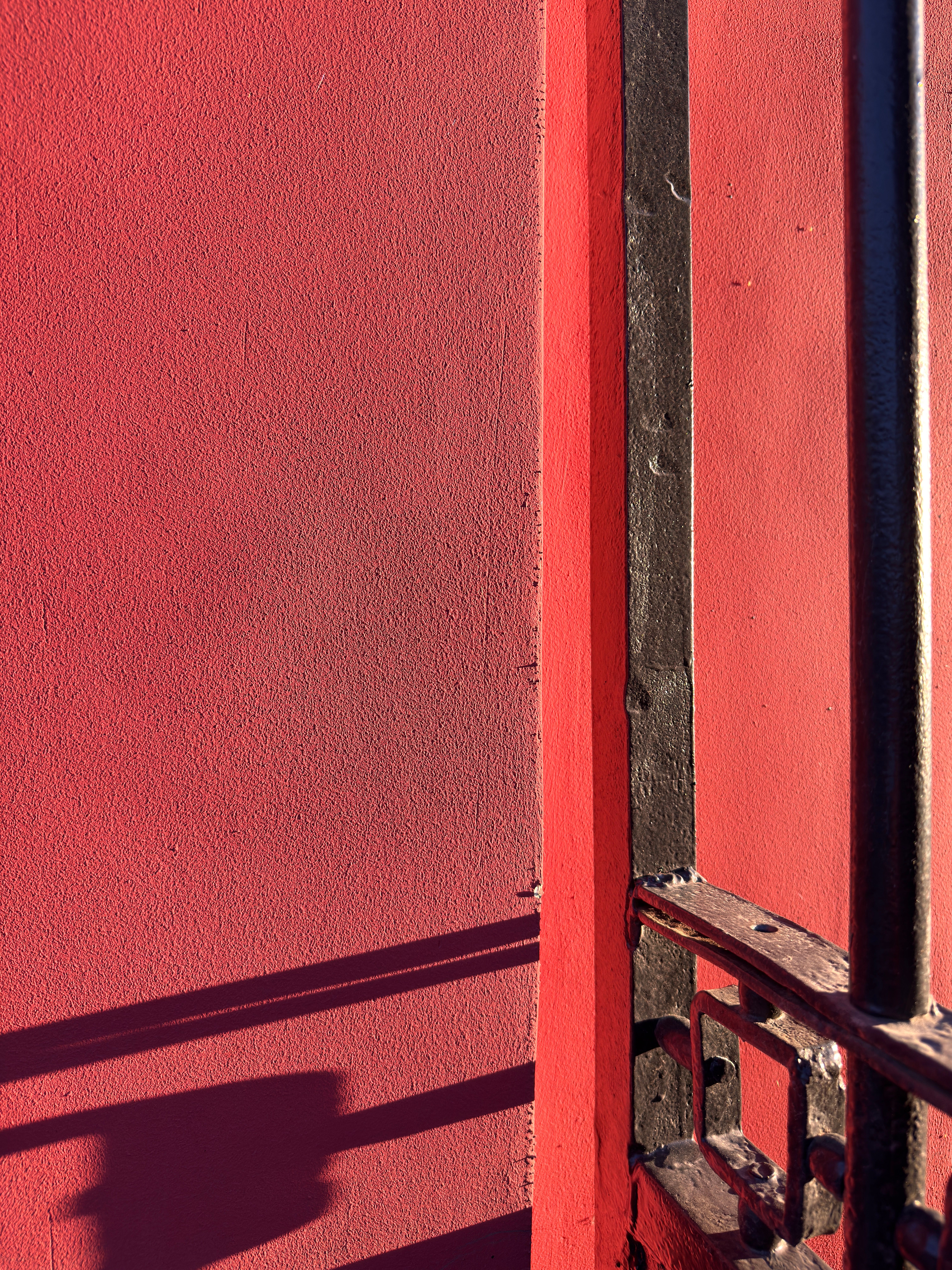 Red Wall with Black Iron Railings in Sunlight · Free Stock Photo