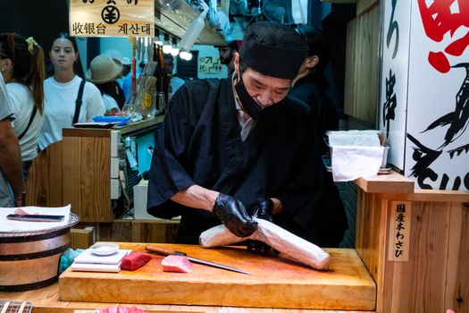 Sushi chef preparing fresh fish at a bustling Kyoto market stall.