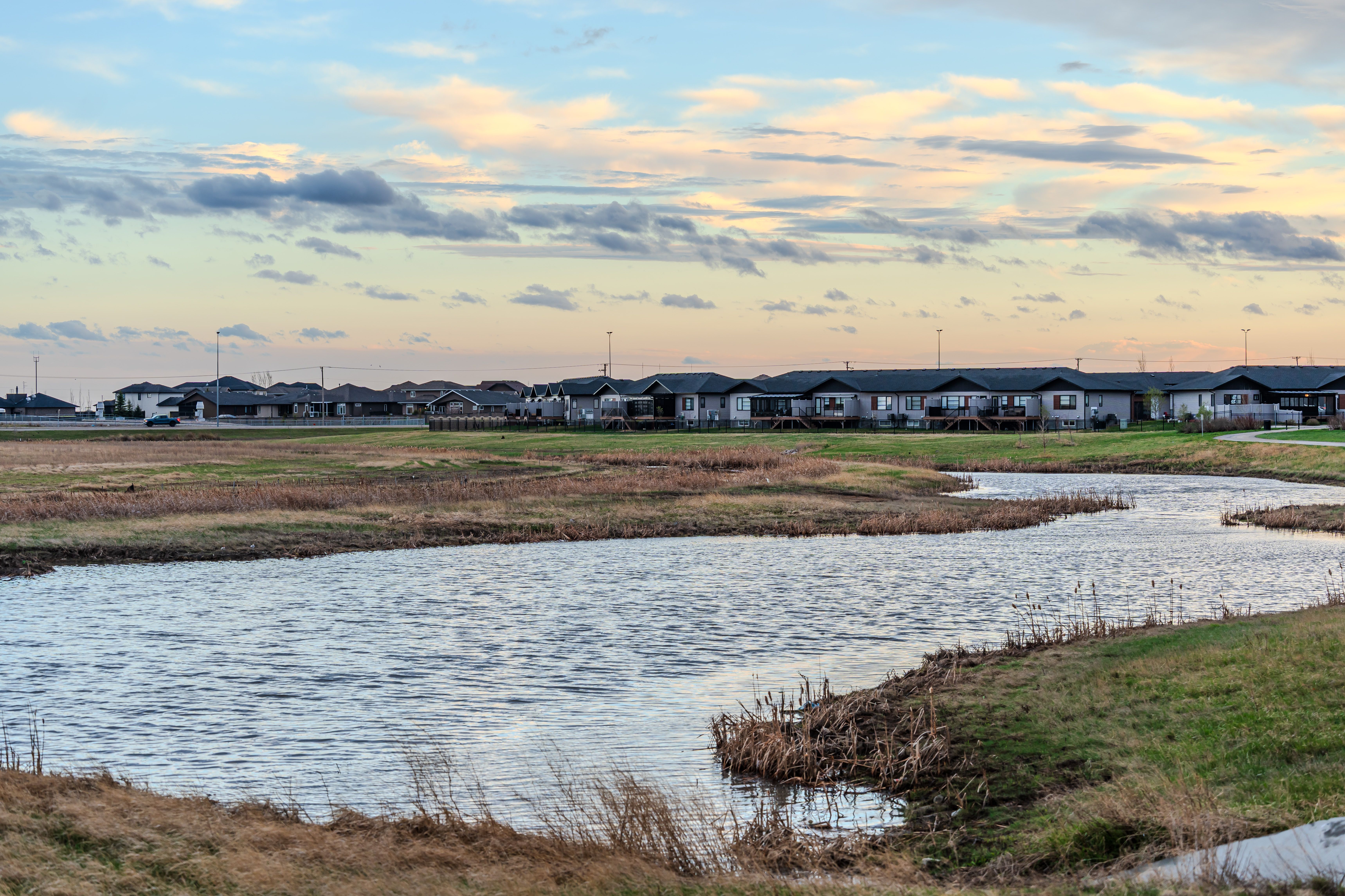 Captivating sunset view over suburban homes with a tranquil water body reflecting the evening sky.