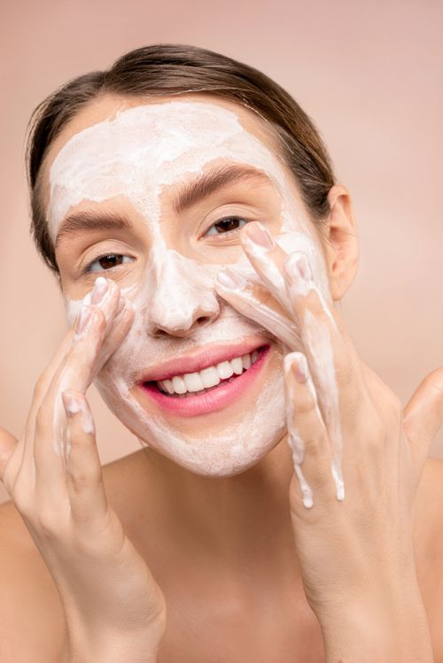 Free A joyful woman applies facial cleanser, promoting skincare routine. Stock Photo