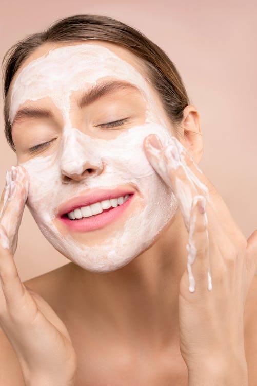 Free Woman Smiling While Cleaning Her Face Stock Photo