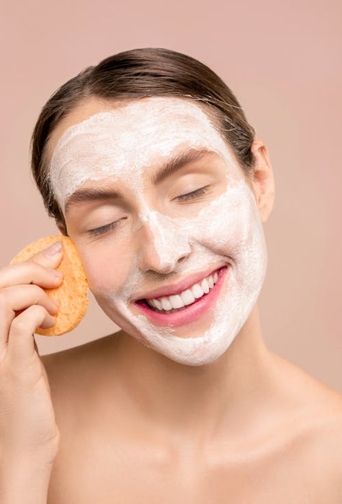 Free Woman Smiling While Cleaning Her Face Stock Photo