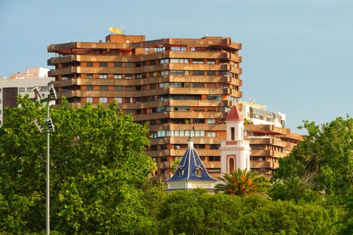 Free A blend of modern and classic architecture surrounded by lush greenery under a clear sky. Stock Photo