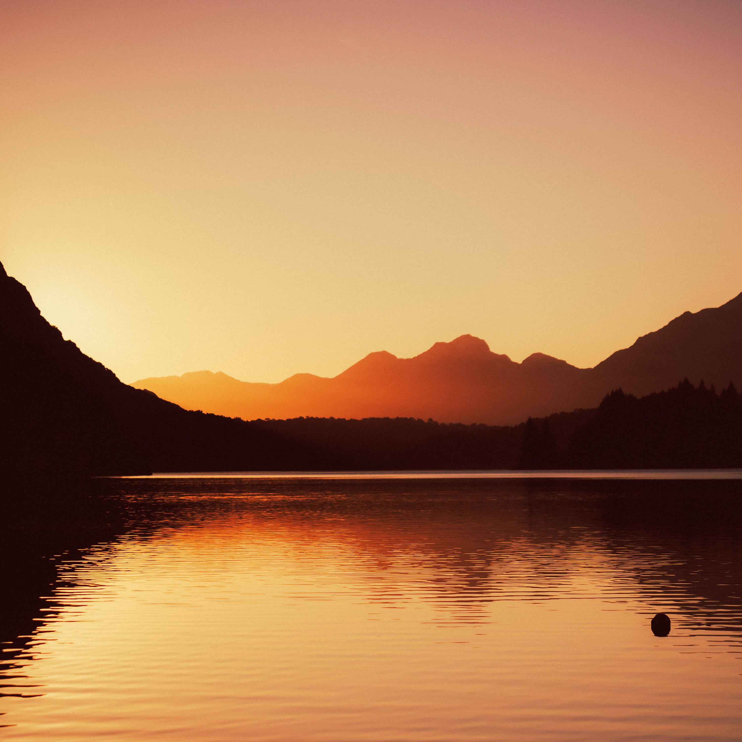 Breathtaking sunset view of mountain silhouettes and calm lake in San Carlos de Bariloche, Argentina.