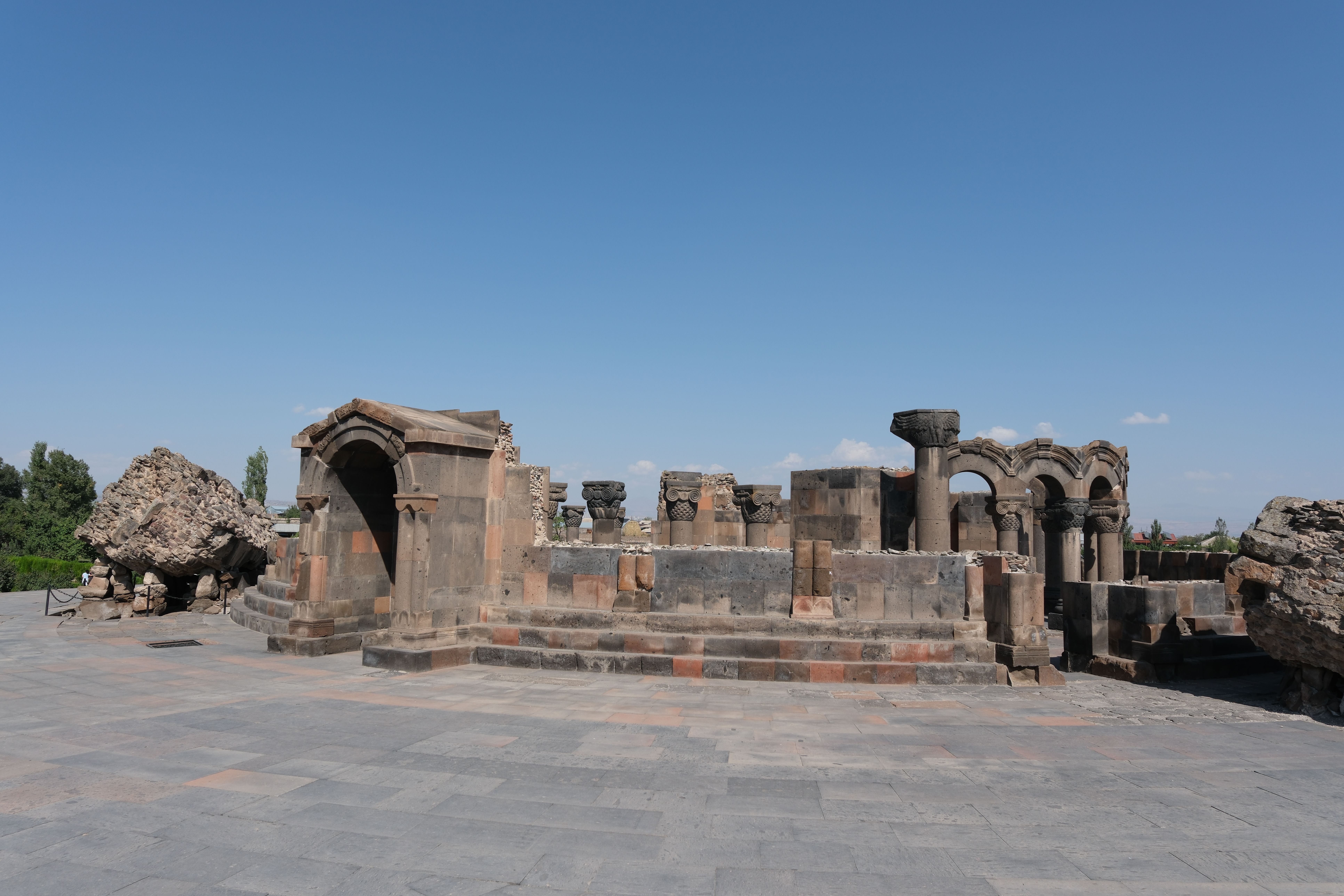 Explore the ancient ruins of Zvartnots Cathedral, showcasing Armenian architectural heritage under a clear blue sky.