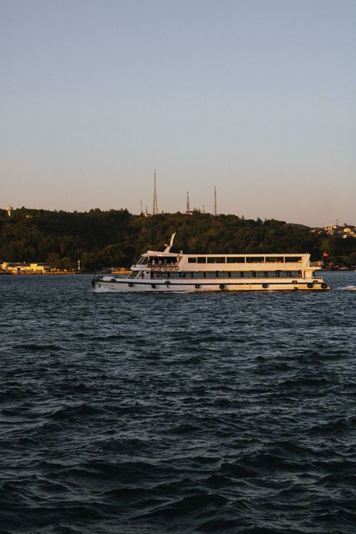 Free White boat cruising on Istanbul's waters under clear skies at sunset. Stock Photo