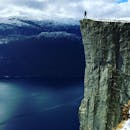 在挪威罗加兰的峡湾之上，一位孤独的冒险家站在普里克斯登山顶俯瞰