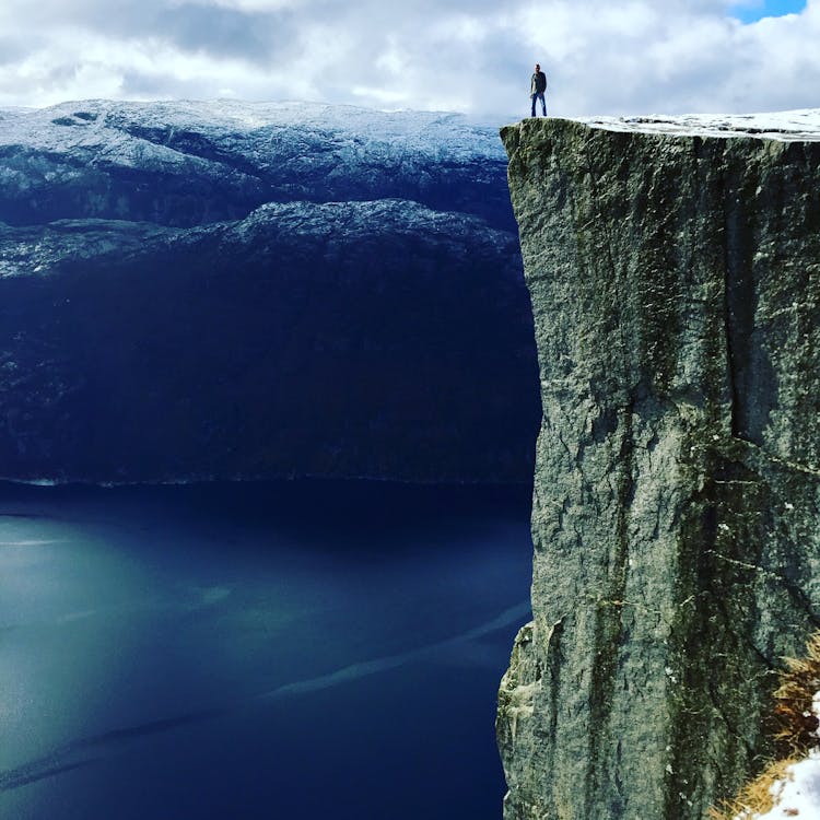 Person Standing At The  Edge Of Rock Formation 