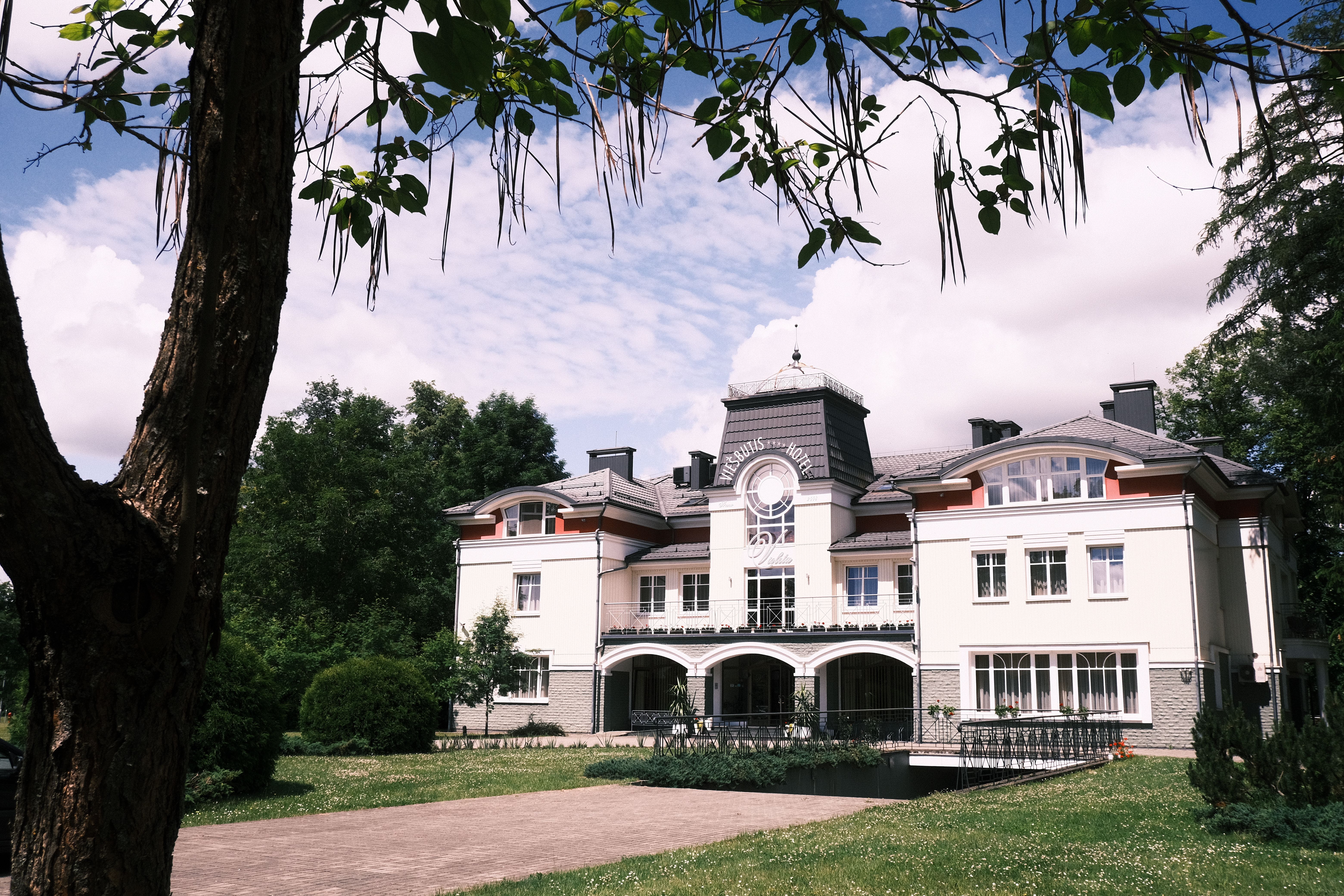 Elegant architecture of Druskininkai's Grand Spa Hotel surrounded by lush greenery.