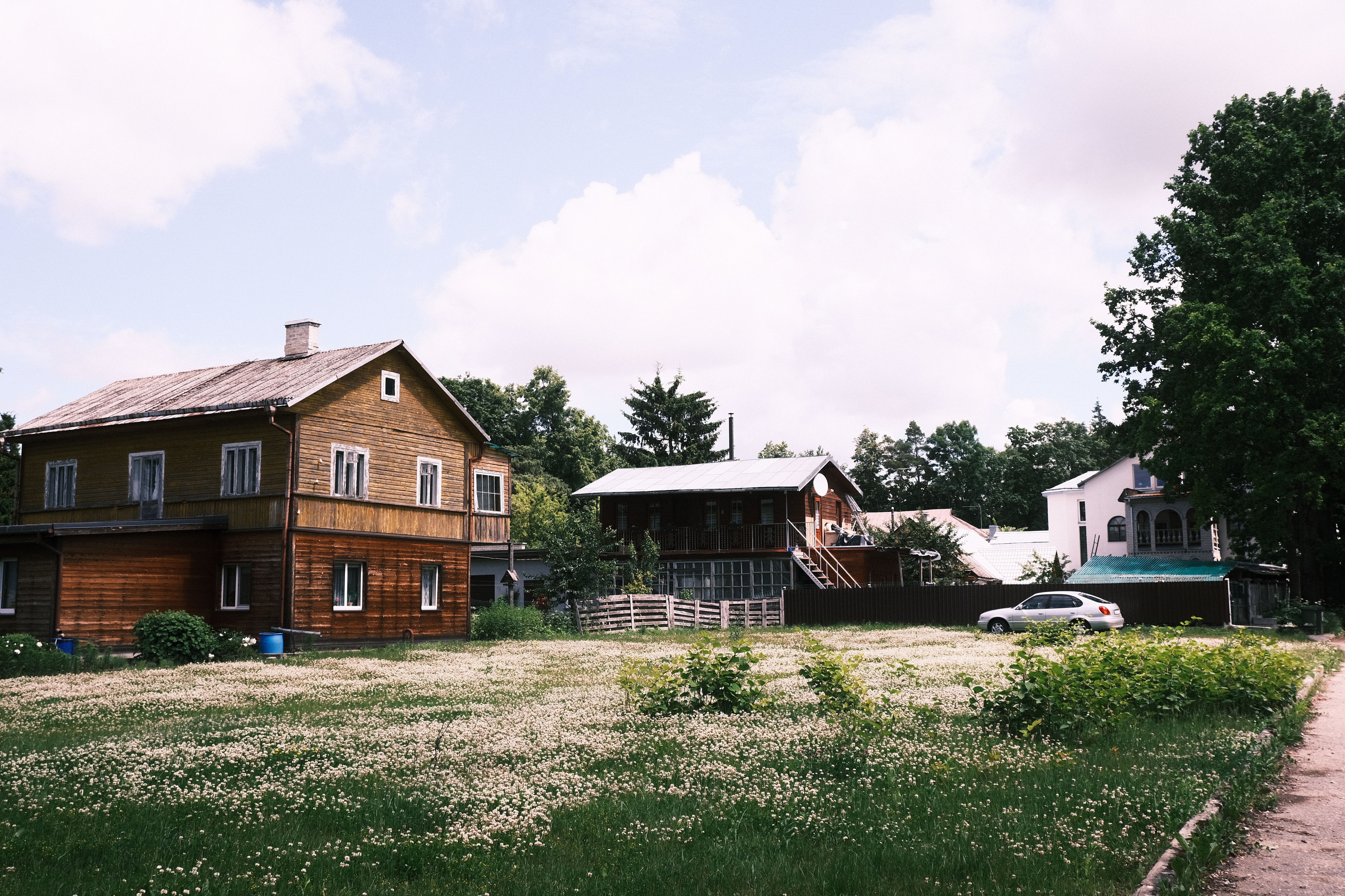 Traditional Latvian guesthouse exterior in a scenic rural setting, surrounded by nature.
