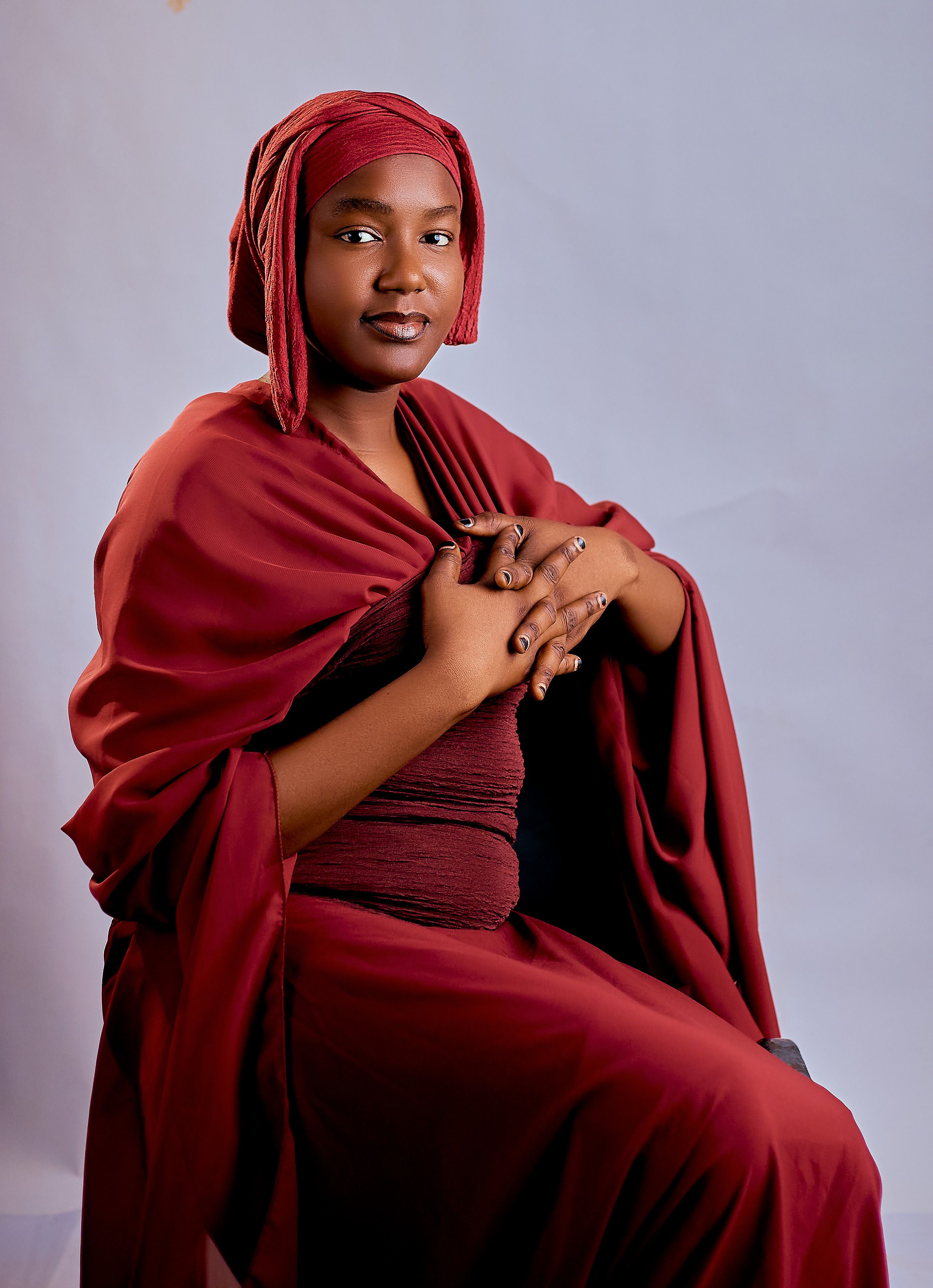 Elegant portrait of a woman in a red hijab on a plain background. Calm and poised.