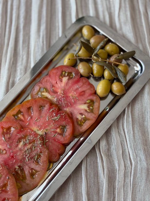 Free Close-up of sliced heirloom tomatoes and green olives on a silver tray. Stock Photo