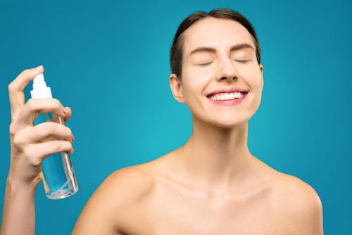 Smiling Topless Woman Holding Clear Glass Bottle