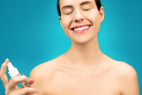 Topless Woman Smiling While Holding Spray Bottle