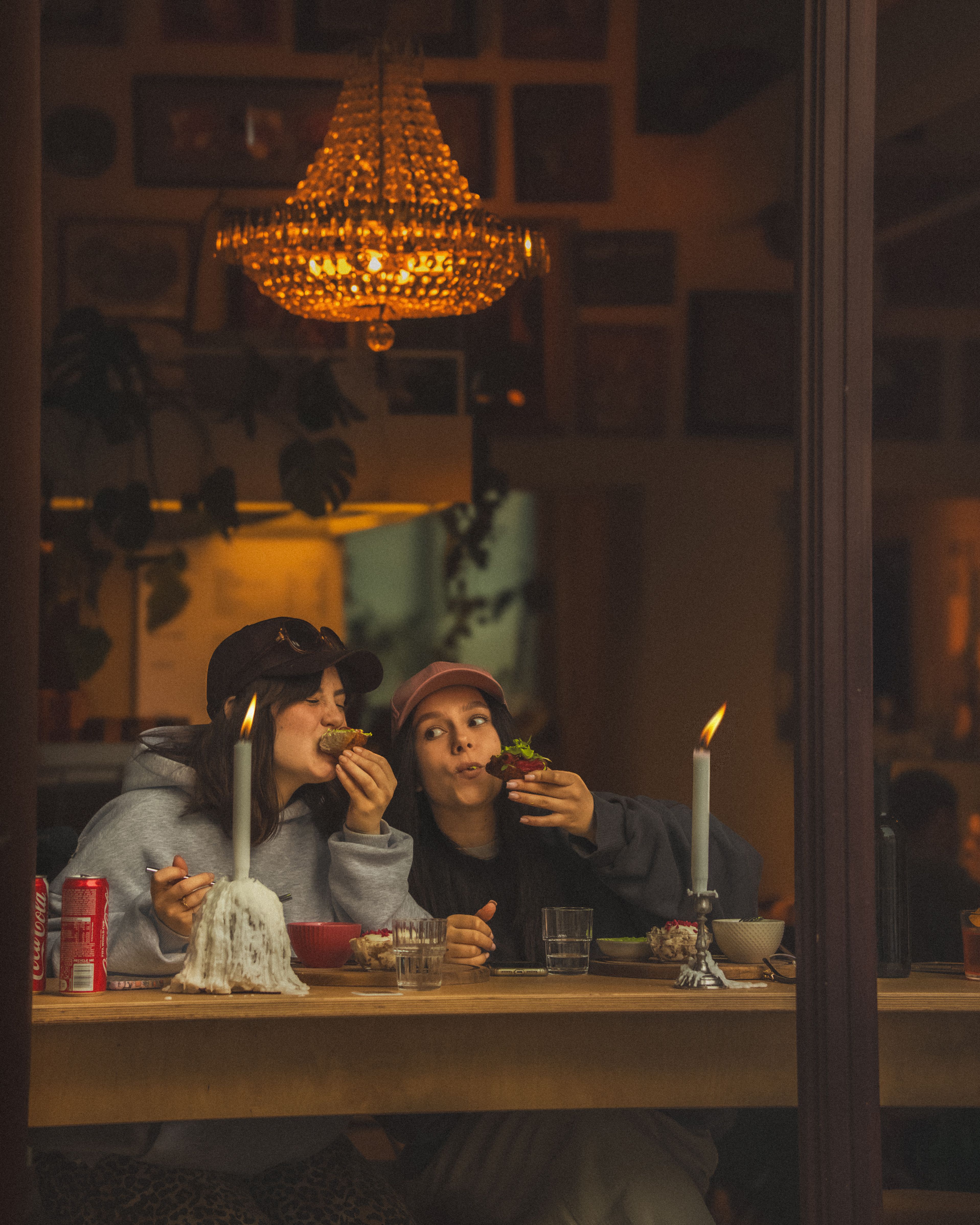 Two women enjoying a candlelit meal in a cozy Warsaw cafe, creating a warm atmosphere.