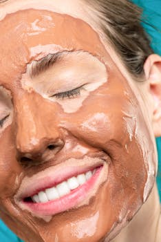 一名微笑着戴棕色粘土面膜的女性特写，用于护肤和放松