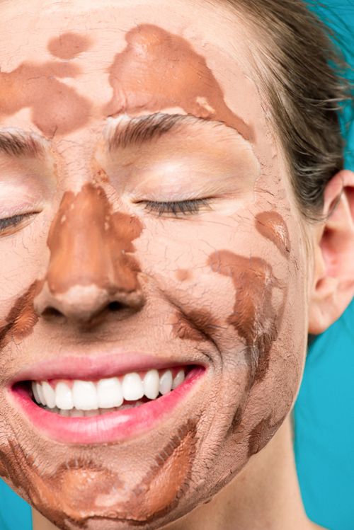 Free Close-up of a smiling woman with a clay face mask for skincare and relaxation. Stock Photo