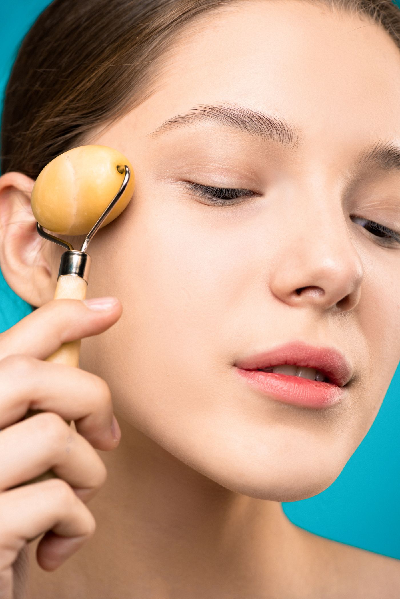 Woman using a facial roller as part of a skincare ritual