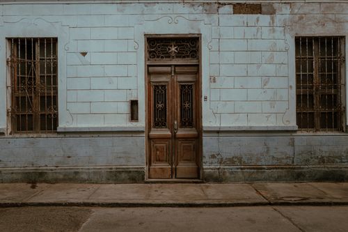 Free A rustic colonial facade with weathered doors and barred windows in Pacasmayo, Peru. Stock Photo