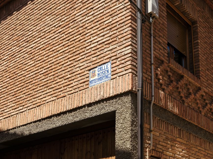 Fachada de edificio de ladrillo con letrero de la calle Calle Mosen Mateo Martínez en Daroca, España.