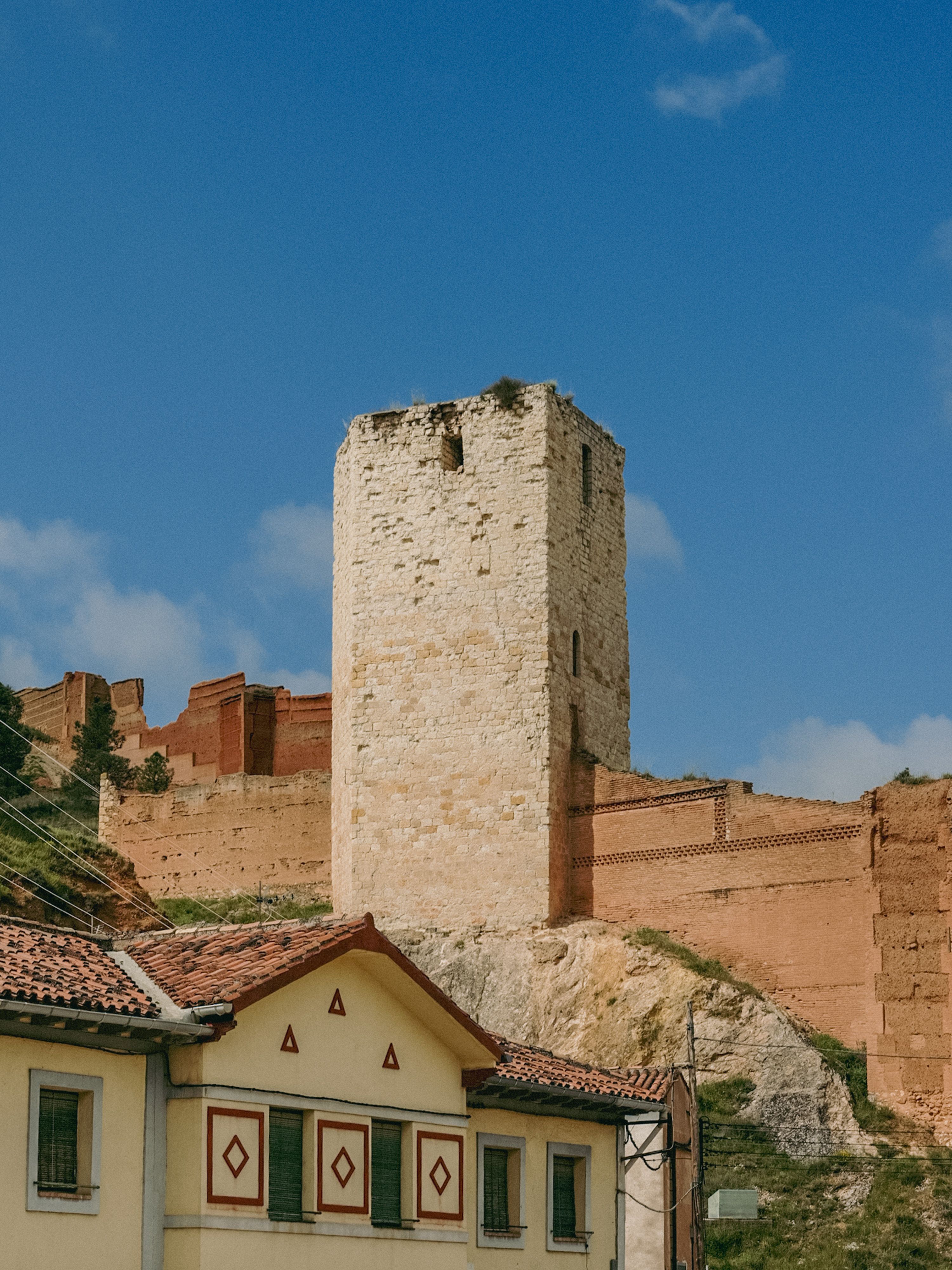 Ancient stone tower and fortress wall in Daroca, Aragon, Spain under a clear blue sky.
