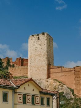 Ancient stone tower and fortress wall in Daroca, Aragon, Spain under a clear blue sky.