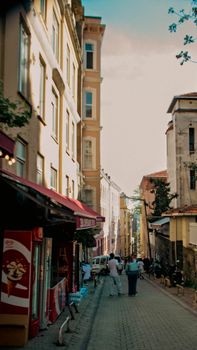 A picturesque European street lined with buildings, a few people enjoying a sunny day.