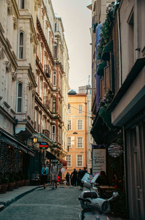 Free Charming alley in a European city with vintage architecture, bustling with pedestrians and cafes. Stock Photo