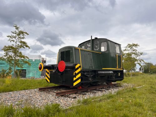 Free A vintage green locomotive parked on the tracks amidst a field under a cloudy sky. Stock Photo