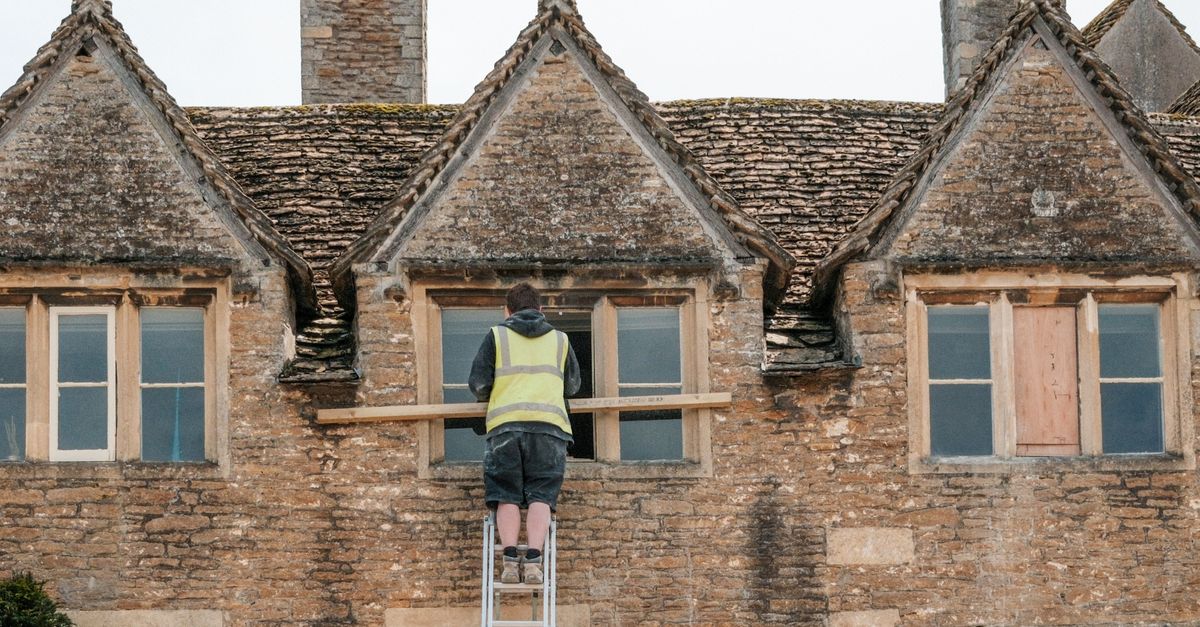 A worker repairing the facade of a stone building — repair and maintenance work is the most resilient segment of the UK trades market