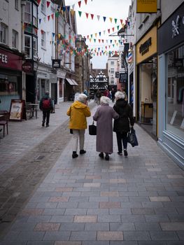 A picturesque city street lined with shops and people strolling under colorful bunting.