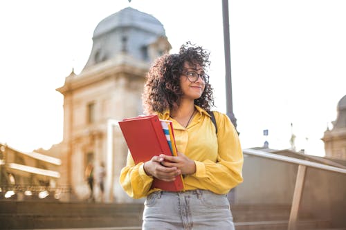 Free 拿着红色书的黄夹克的女人 Stock Photo