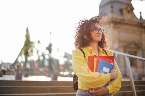 Free Selective Focus Photo of Woman in Yellow Long Sleeve Shirt and Glasses Carrying Folders  Stock Photo